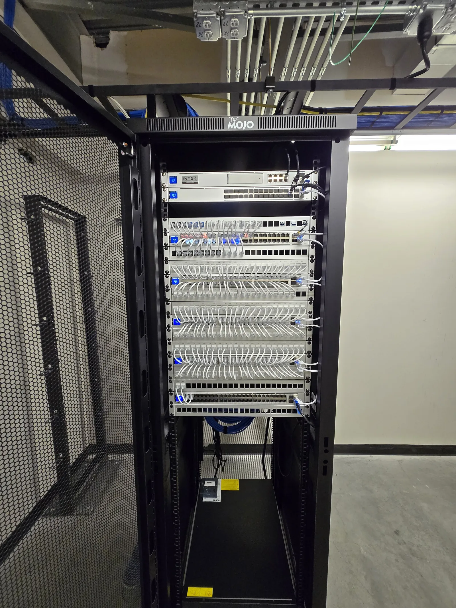 Full-height network rack with combed white patch cabling installed by INTEK